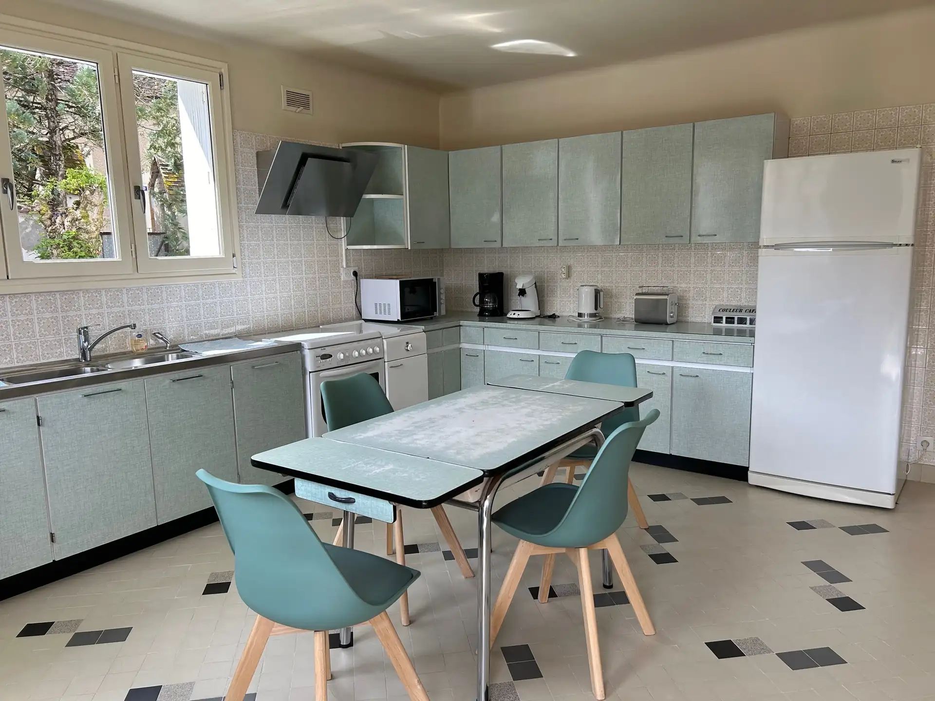 Fitted kitchen with pale green cabinets and a central table