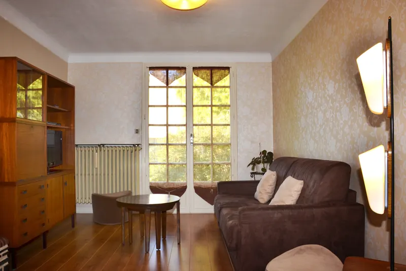 Family lounge with sofa, wooden sideboard and French doors onto the garden